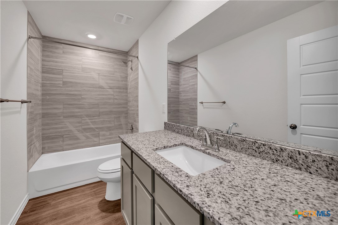203 Wind Ridge Drive Copperas Cove, TX 76522 - Photo 12 of 16 a bathroom with a granite countertop sink a toilet and bathtub