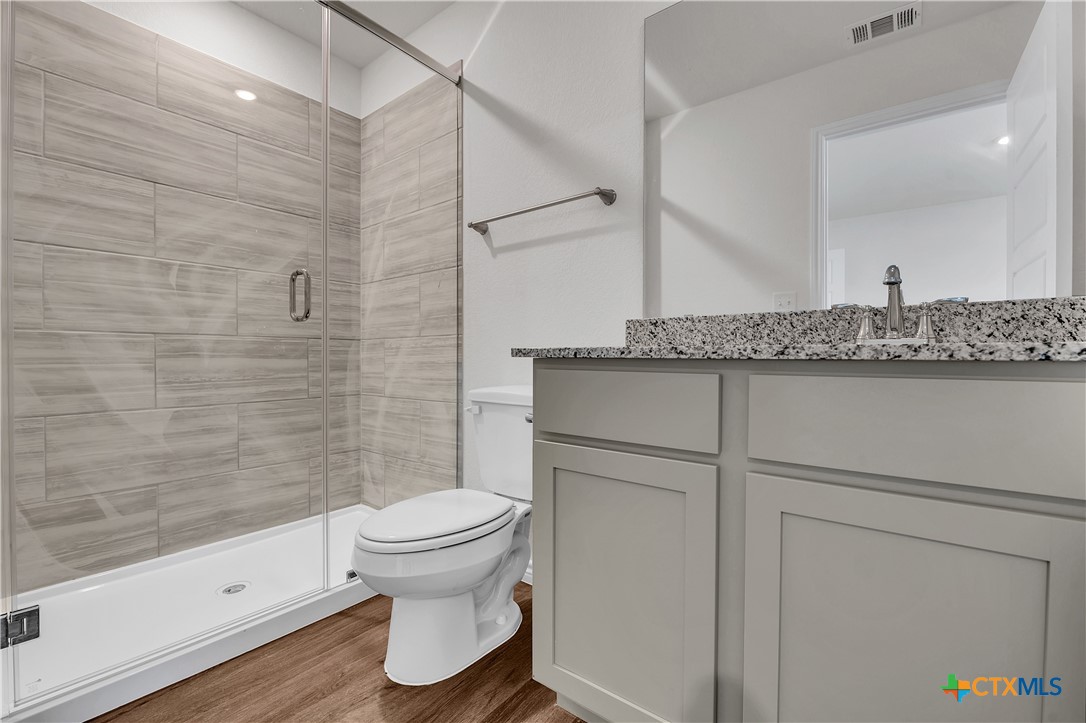 203 Wind Ridge Drive Copperas Cove, TX 76522 - Photo 14 of 16 a bathroom with a granite countertop toilet a sink and a shower
