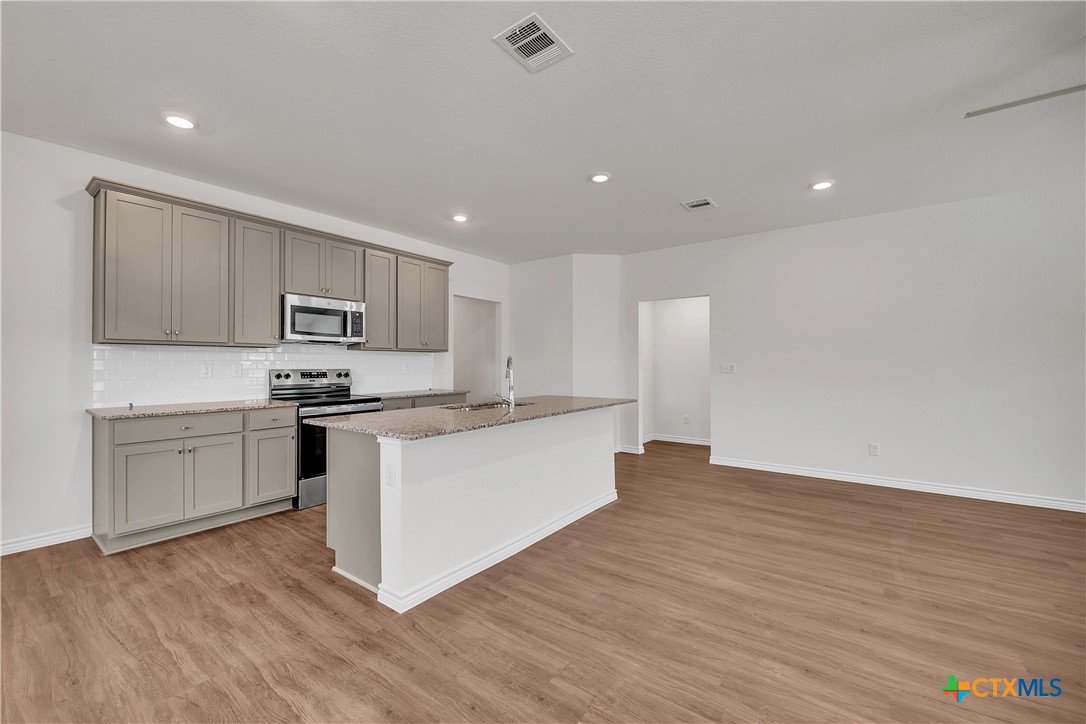 203 Wind Ridge Drive Copperas Cove, TX 76522 - Photo 4 of 16 a kitchen with granite countertop white cabinets and stainless steel appliances
