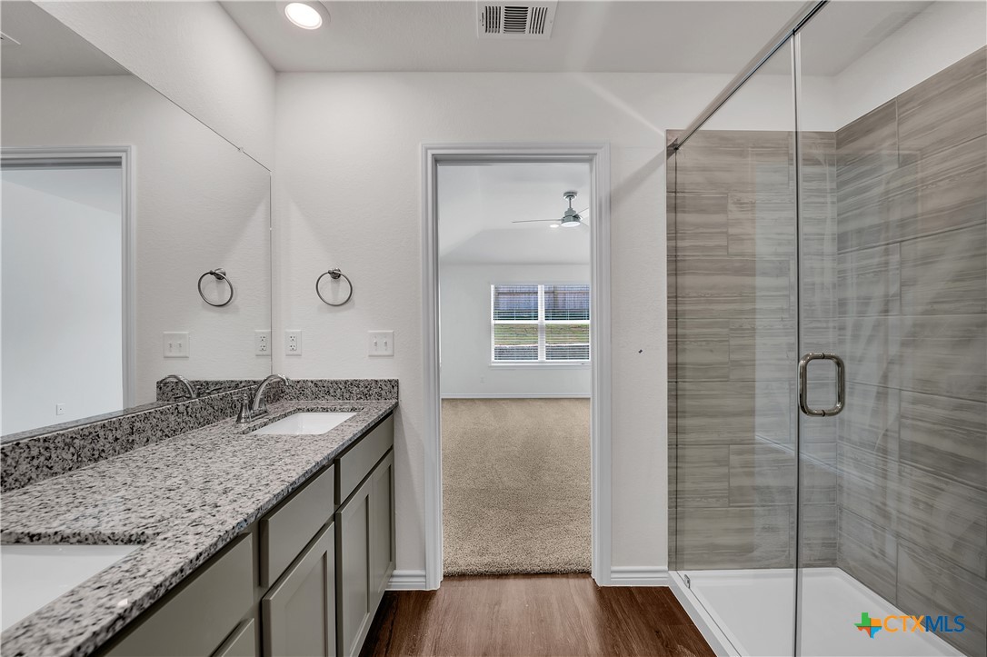 203 Wind Ridge Drive Copperas Cove, TX 76522 - Photo 8 of 16 a bathroom with a granite countertop sink a mirror and shower