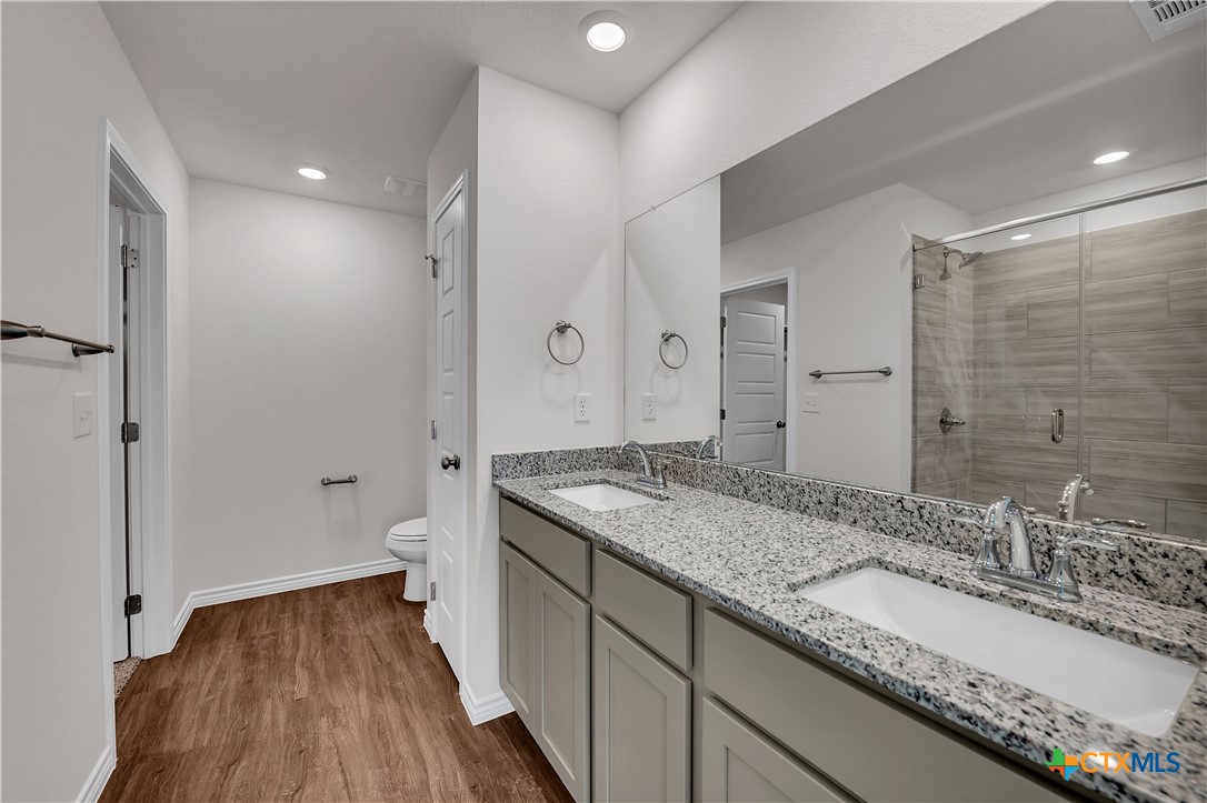 203 Wind Ridge Drive Copperas Cove, TX 76522 - Photo 9 of 16 a bathroom with a granite countertop sink a toilet and a large mirror