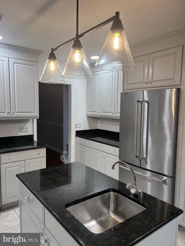 a kitchen with stainless steel appliances granite countertop a sink a refrigerator and a granite counter top