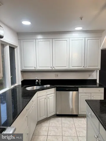 a kitchen with granite countertop white cabinets and sink