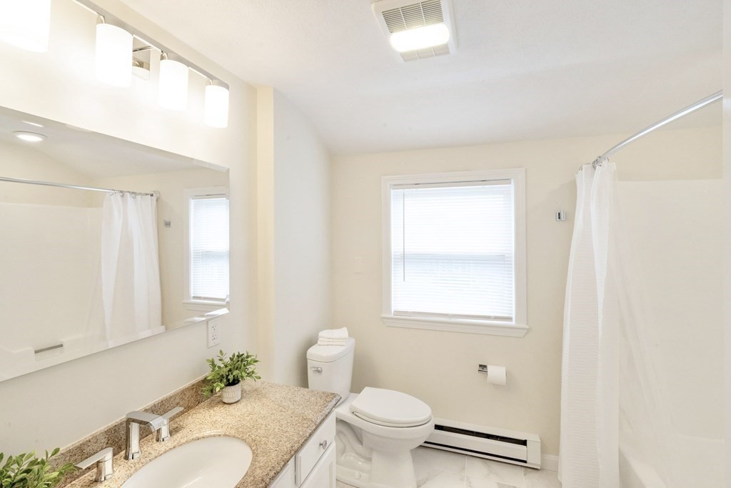 129 Watervale Road, Unit 129 Medford, MA 02155 - Photo 18 of 29 a bathroom with a granite countertop sink toilet a mirror and a shower