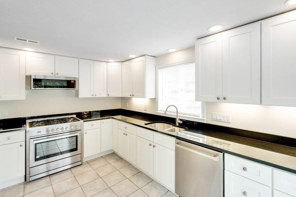 129 Watervale Road, Unit 129 Medford, MA 02155 - Photo 2 of 29 a kitchen with granite countertop white cabinets and white appliances