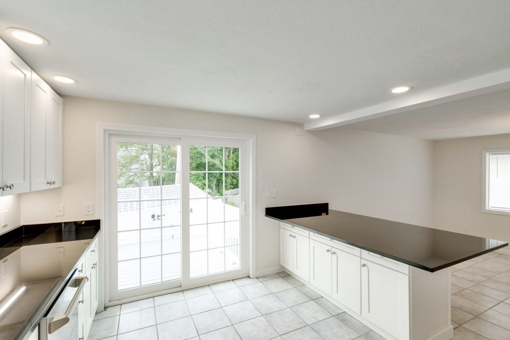 129 Watervale Road, Unit 129 Medford, MA 02155 - Photo 4 of 29 a kitchen with granite countertop a stove a sink and a microwave