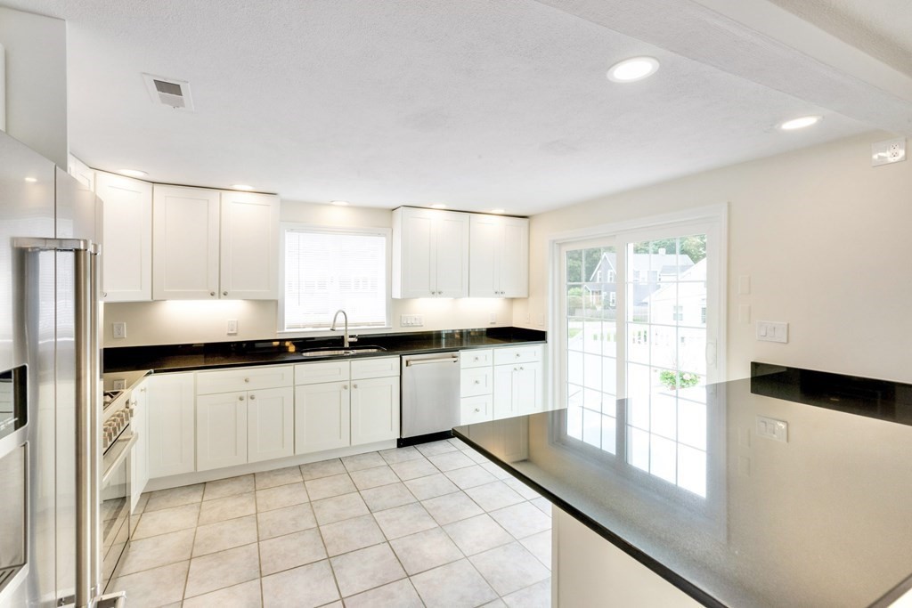 129 Watervale Road, Unit 129 Medford, MA 02155 - Photo 5 of 29 a kitchen with granite countertop white cabinets white appliances a sink and a large window