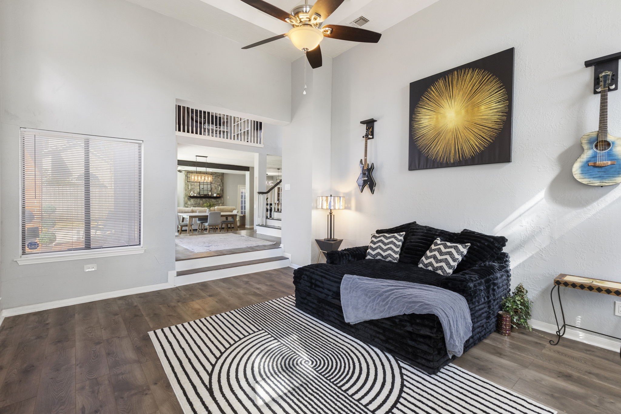 2110 Paso Rello Drive Houston, TX 77077 - Photo 6 of 41 This inviting living area features high ceilings and vinyl hardwood floors. The space is brightened by natural light from a window, leading to a dining area and staircase, creating an open and airy atmosphere.
