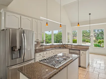 a kitchen with stainless steel appliances granite countertop a refrigerator a sink and a stove