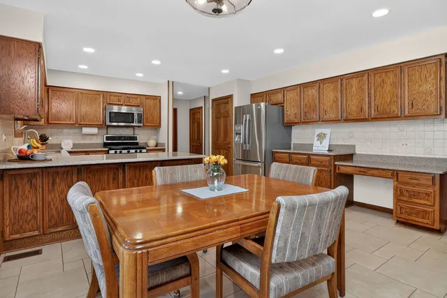 a kitchen with stainless steel appliances kitchen island granite countertop a sink a stove a kitchen island with chairs and white cabinets