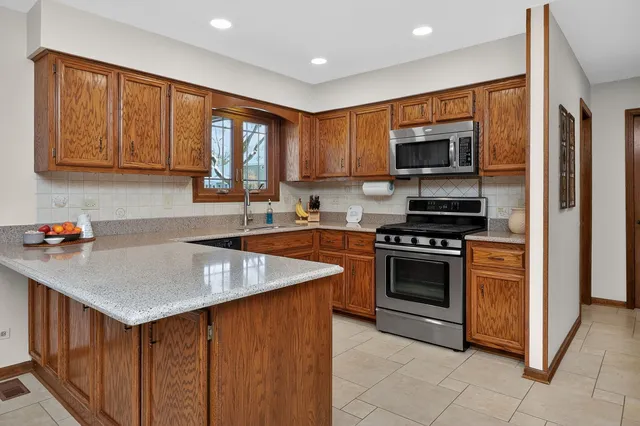 a kitchen with stainless steel appliances granite countertop a sink stove refrigerator and a microwave oven