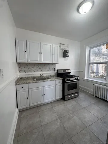 a kitchen with granite countertop a stove a sink and dishwasher