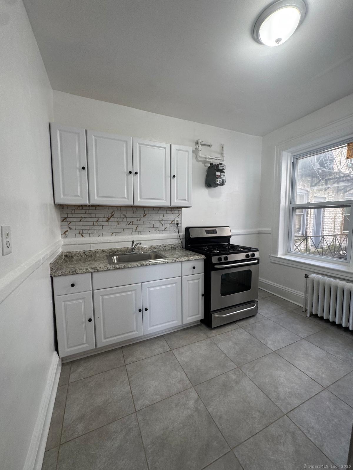 a kitchen with granite countertop a stove a sink and dishwasher