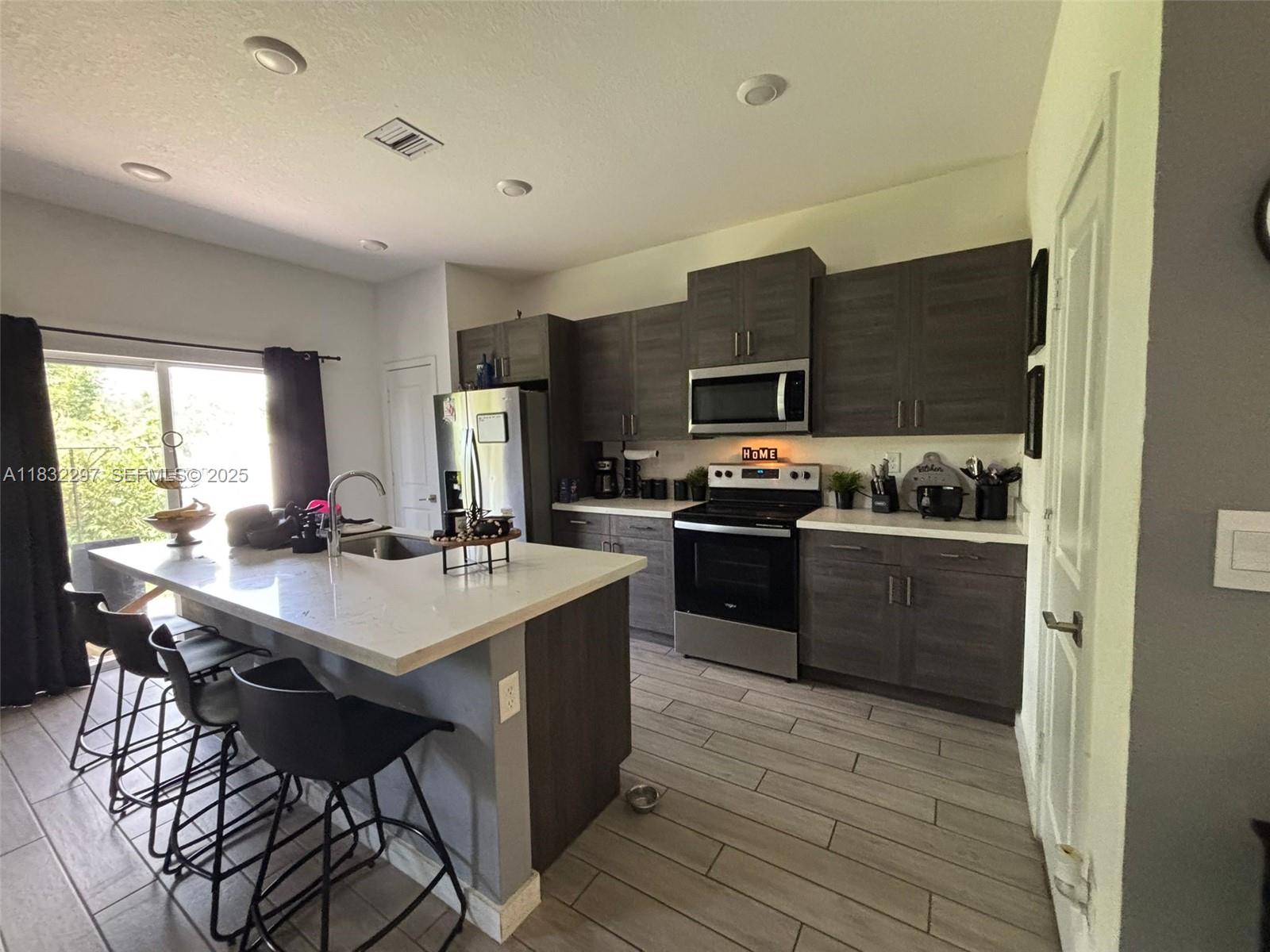 830 Southeast 19th Street Homestead, FL 33034 - Photo 3 of 16 a kitchen with stainless steel appliances a sink a stove a refrigerator cabinets and dining table
