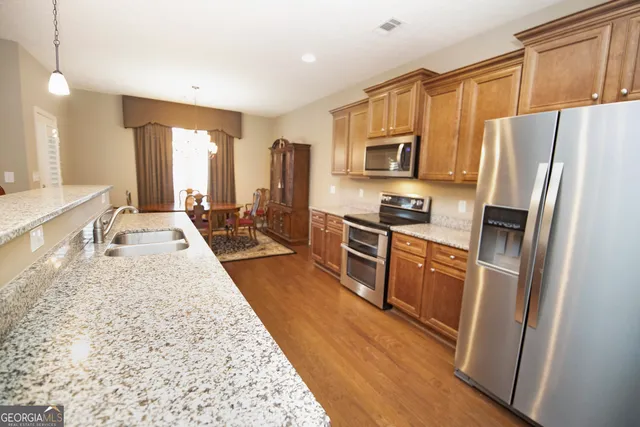a large kitchen with stainless steel appliances granite countertop a refrigerator stove microwave and sink