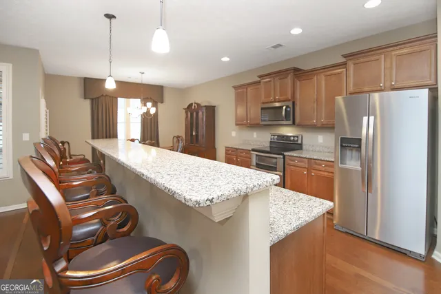 a living room with stainless steel appliances granite countertop furniture wooden floor and a view of kitchen