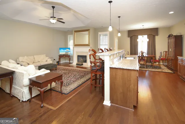 a living room with stainless steel appliances furniture a rug and a large window