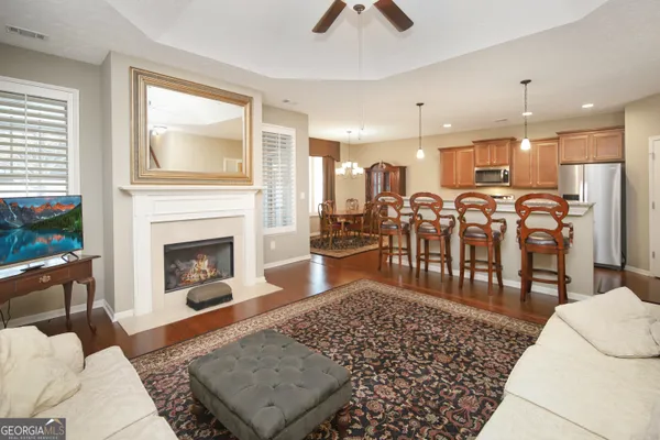 a living room with stainless steel appliances furniture a rug and a large window
