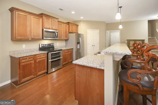 a kitchen with stainless steel appliances granite countertop a stove a sink dishwasher and a refrigerator with wooden floor