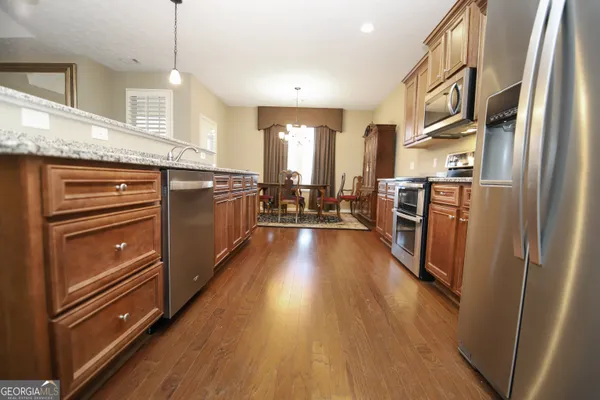 a kitchen with stainless steel appliances granite countertop a refrigerator a stove and a wooden floors