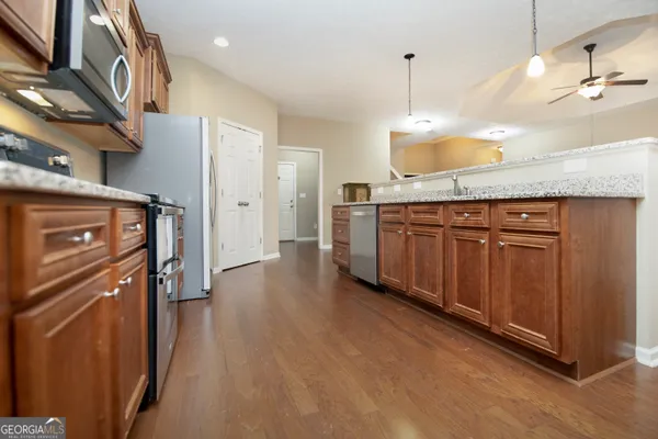a kitchen with stainless steel appliances granite countertop a refrigerator a oven and a stove with wooden floors