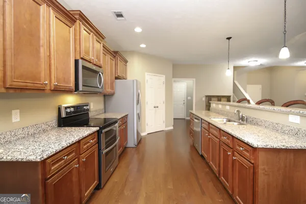 a kitchen with stainless steel appliances granite countertop a kitchen island a stove a sink and a microwave