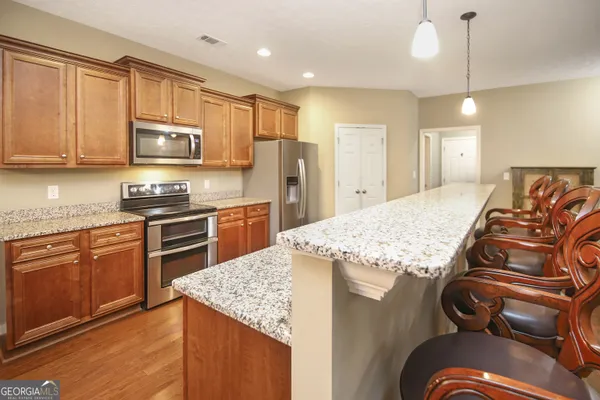 a kitchen with kitchen island granite countertop a stove top oven a sink a counter space and cabinets