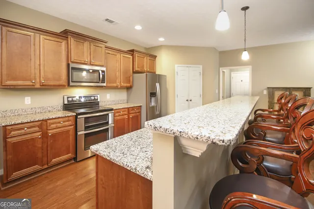 a kitchen with kitchen island granite countertop a stove top oven a sink a counter space and cabinets