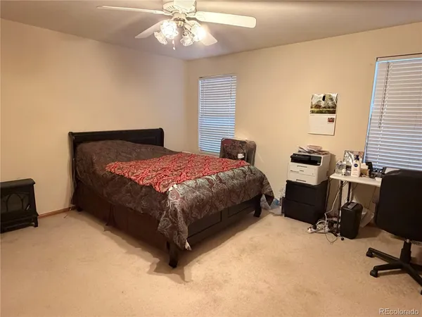 a bedroom with a bed computer on desk and a dresser