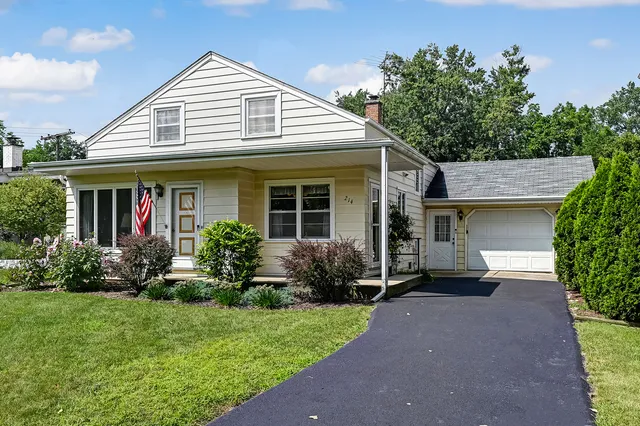 a view of a white house with potted plants and a table and chairs