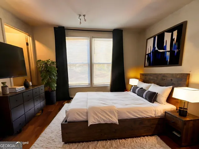 a bedroom with a bed flat screen tv and a window