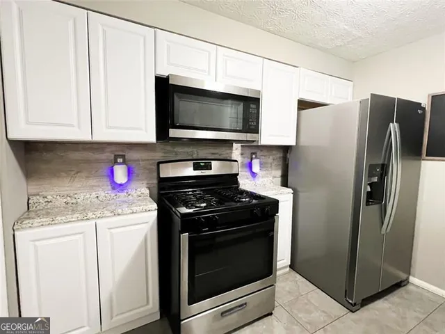 a kitchen with stainless steel appliances granite countertop a refrigerator stove and microwave