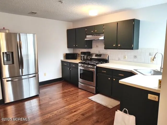 a kitchen with stainless steel appliances a sink a stove a microwave a refrigerator a sink and a refrigerator