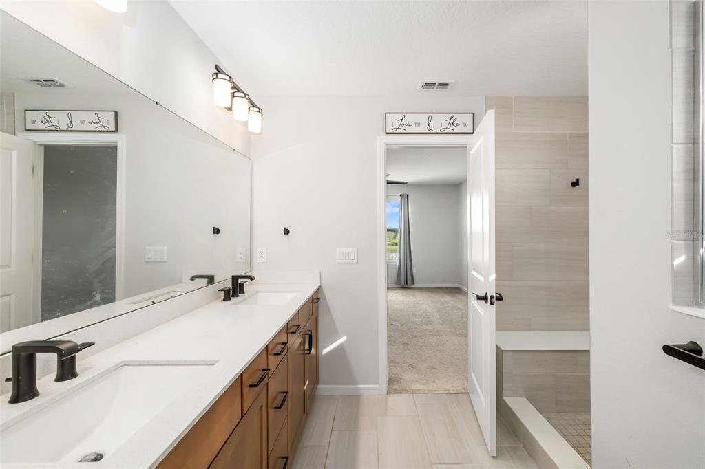 9406 Lamine Way Parrish, FL 34219 - Photo 30 of 74 a bathroom with a double vanity sink a mirror and a shower