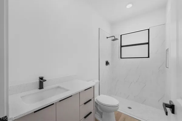 a bathroom with a granite countertop sink a toilet and shower