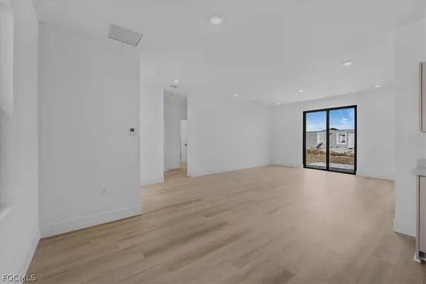 a view of an empty room with wooden floor and windows