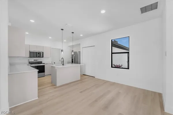 a view of kitchen with kitchen island stainless steel appliances refrigerator stove microwave and cabinets