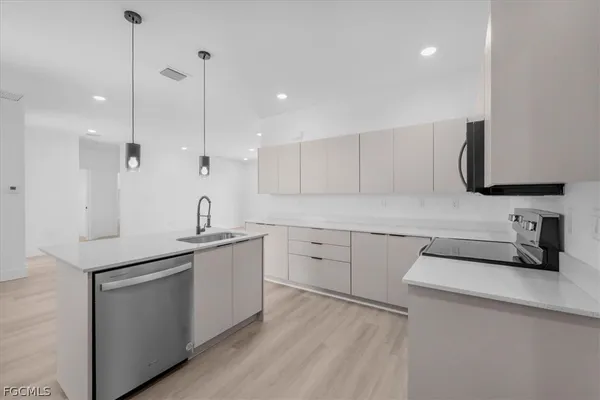 a kitchen with a sink dishwasher a stove and white cabinets with wooden floor