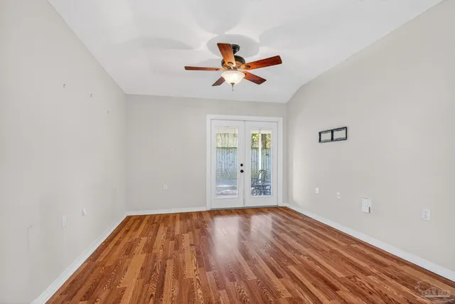 a view of kitchen and empty room with wooden floor