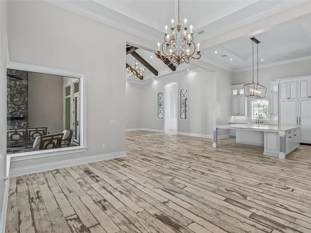 wooden floor in an empty room with a chandelier fan