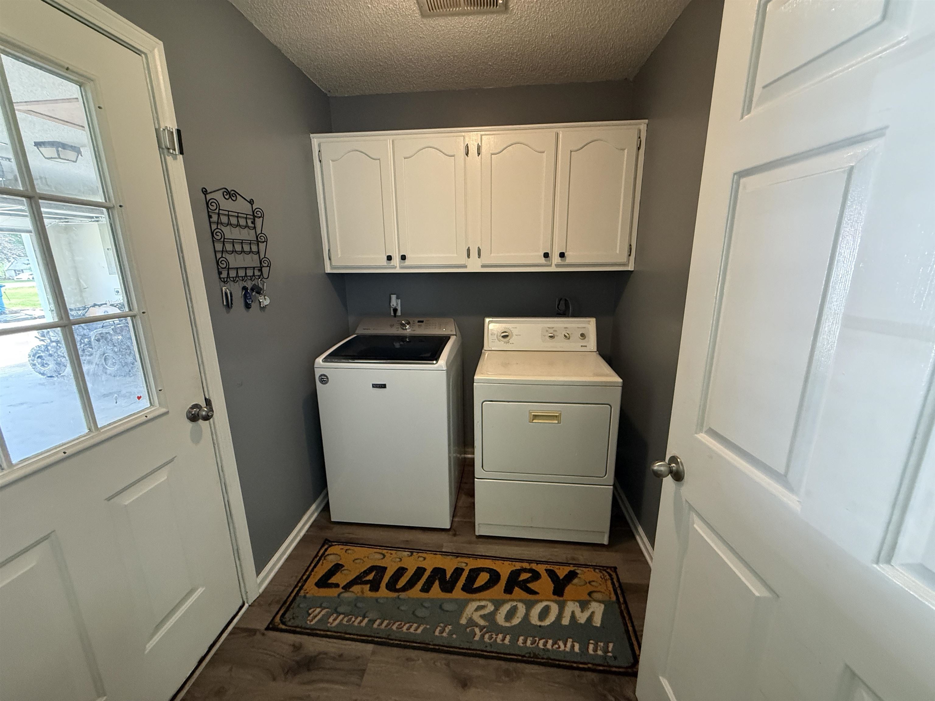185 Mignon Road Atoka, TN 38004 - Photo 28 of 34 Dedicated laundry area featuring overhead white cabinetry with black hardware, wood-finish flooring, and light gray walls