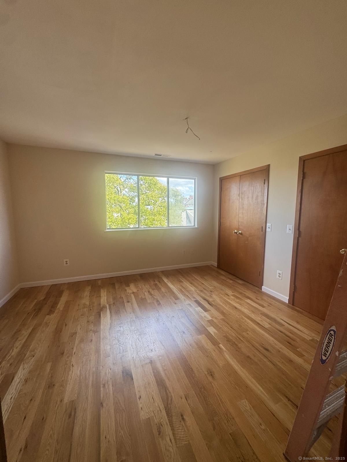 204 Wheeler Avenue, Unit 6 Bridgeport, CT 06606 - Photo 5 of 15 a view of an empty room with wooden floor and window