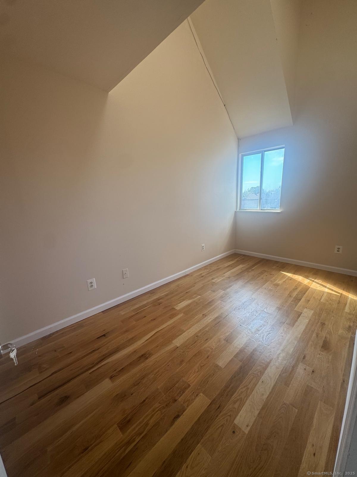 204 Wheeler Avenue, Unit 6 Bridgeport, CT 06606 - Photo 6 of 15 an empty room with wooden floor and windows