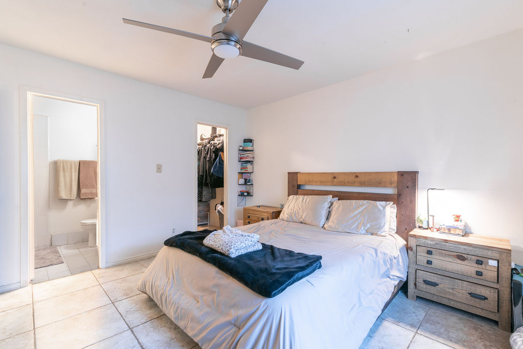 1106 Saucedo Street Austin, TX 78721 - Photo 20 of 34 Bedroom with tile patterned floors, a spacious closet, ensuite bathroom, and a ceiling fan