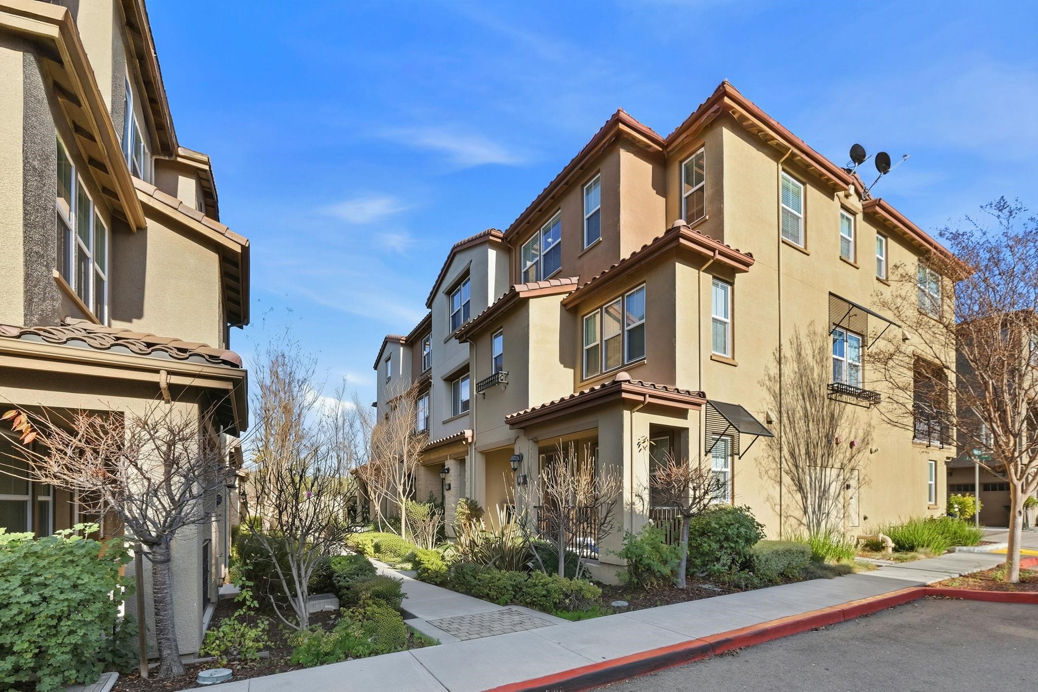 a front view of a residential apartment building with yard and parking