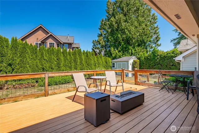 a view of a roof deck with table and chairs couches with wooden floor and fence