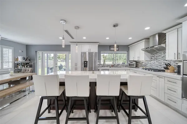 a kitchen with stainless steel appliances kitchen island granite countertop a dining table chairs refrigerator and sink
