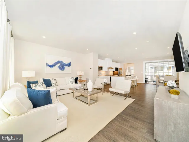 a kitchen with stainless steel appliances kitchen island granite countertop a stove a sink a refrigerator and white cabinets with wooden floor