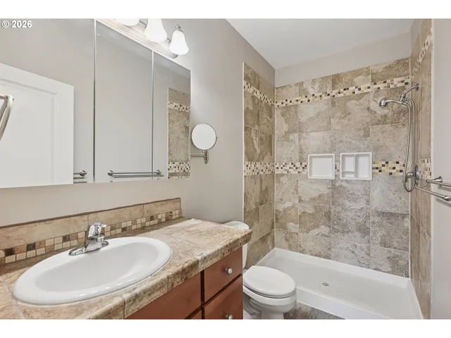 a bathroom with a granite countertop sink toilet mirror and shower