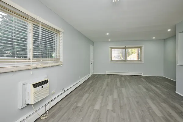 an empty room with wooden floor and windows